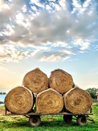 Stack of hay bales on field against sky