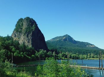 Scenic view of haystack rock by river against clear sky