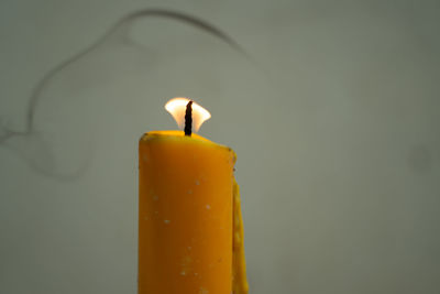 Close-up of lit candle against orange background