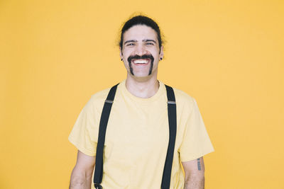 Portrait of happy mature man against yellow background