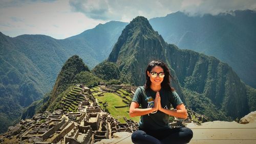 Portrait of smiling woman sitting against mountains