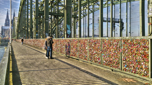 People on hohenzollern bridge by padlocks attached to railing