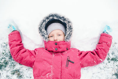 Directly above portrait of girl making snow angel on land