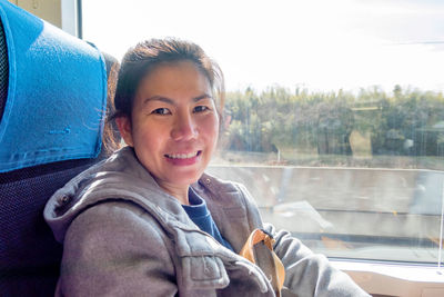 Portrait of smiling woman sitting in train by window