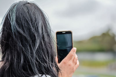 Rear view of woman photographing through smart phone