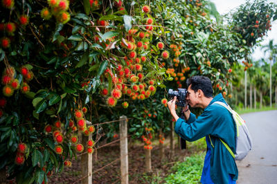 Side view of man photographing against trees