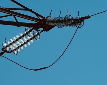 Low angle view of electricity pylon against clear blue sky