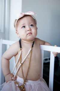 Close-up of cute shirtless baby girl wearing jewelries and headband