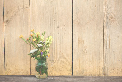 Close-up of flower vase against wooden wall