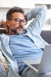 Portrait of man using laptop while sitting on sofa at home