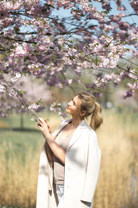 Woman standing by cherry blossom tree