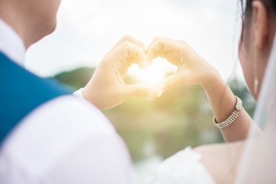 Cropped image of couple making heart shape with hands