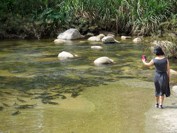 Rear view of man photographing in water