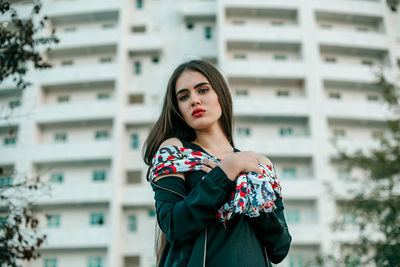 Beautiful young woman standing against buildings