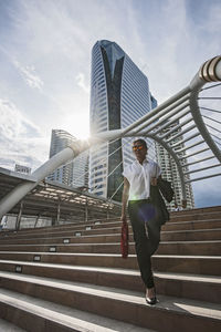 Low angle view of man on staircase in city against sky