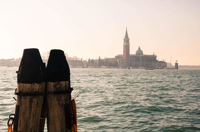 Wooden posts in sea against clear sky