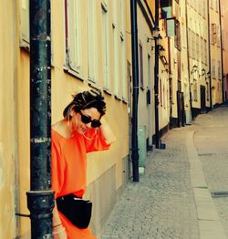 Side view of woman standing by building in city