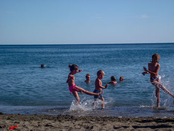 Children on beach against sky