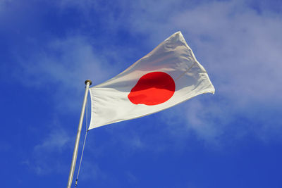 Low angle view of japanese flag against blue sky