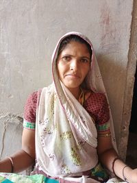 Portrait of a woman sitting against wall