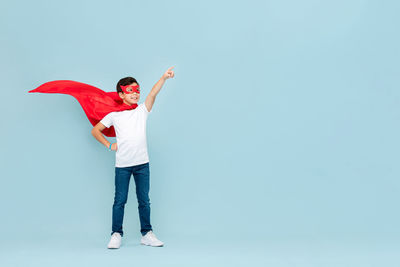 Full length of young man standing against blue background