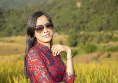 Portrait of smiling young woman wearing sunglasses on field