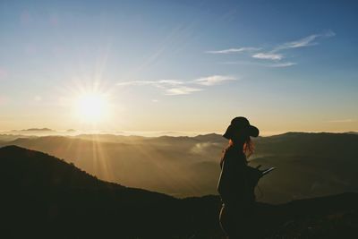 Silhouette woman standing on mountain against sky during sunset