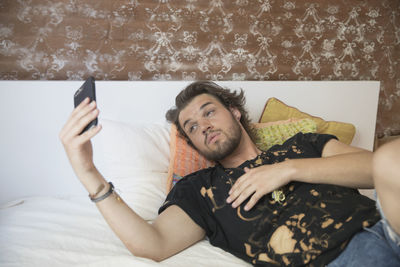 Young man taking a selfie on his bed