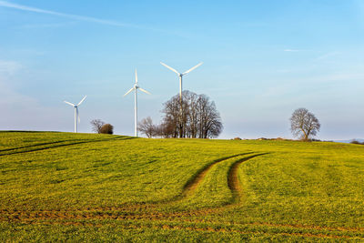 Windmills on field against sky