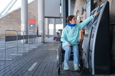 Disabled woman operating ticket vending machine