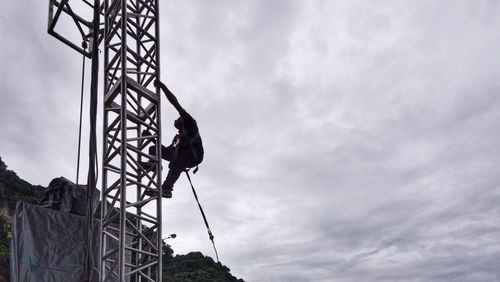 Low angle view of man on rope against sky