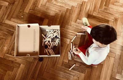 High angle view of boy sitting on hardwood floor at home