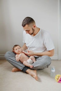 Happy caucasian father holding newborn baby on laps knees. man parent embracing rocking child 