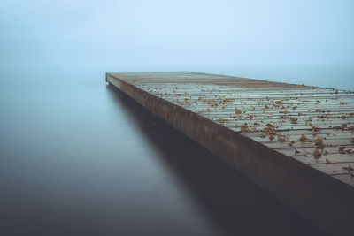 Wooden posts on sea against sky