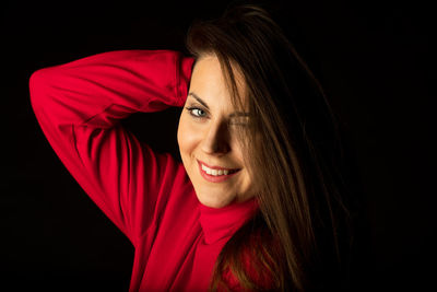 Portrait of smiling woman over black background
