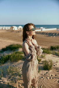 Young woman wearing sunglasses while standing at beach