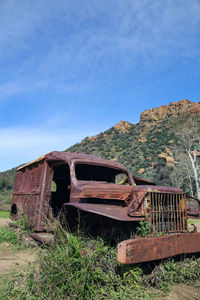 Abandoned vehicle on field against sky