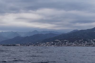 Scenic view of sea by townscape against sky