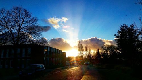 Road passing through city during sunset