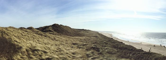 Scenic view of hill by sea against sky