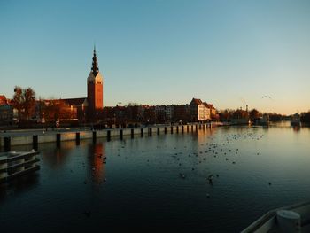 River by buildings against clear sky during sunset