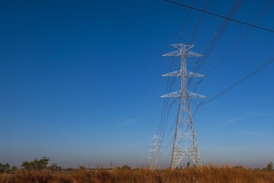 Electric pole and electric cable on the field in the countryside with blue sky.