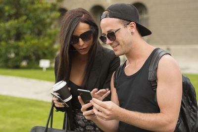 Young couple using mobile phone on street