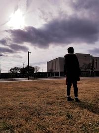 Rear view of man standing on field against sky