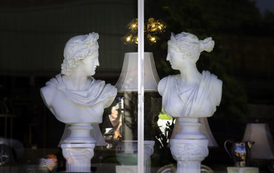 Busts seen through display window of shop