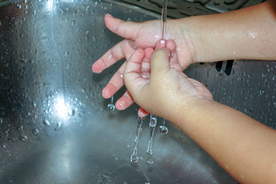 Cropped image of child on wet window during rainy season