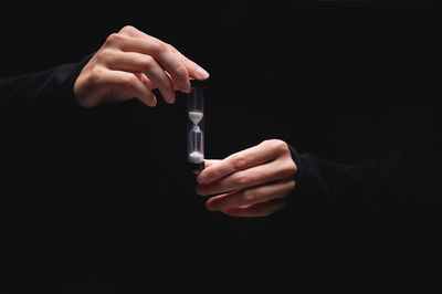 Midsection of man holding cigarette against black background