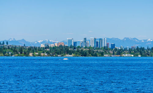 Sea by buildings against blue sky