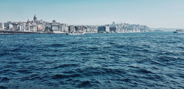 Sea by buildings against clear sky