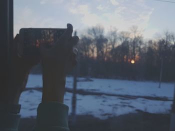 Close-up of person photographing through car windshield during winter